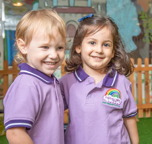 Two smiling children in Rainbow Valley Nursery uniform