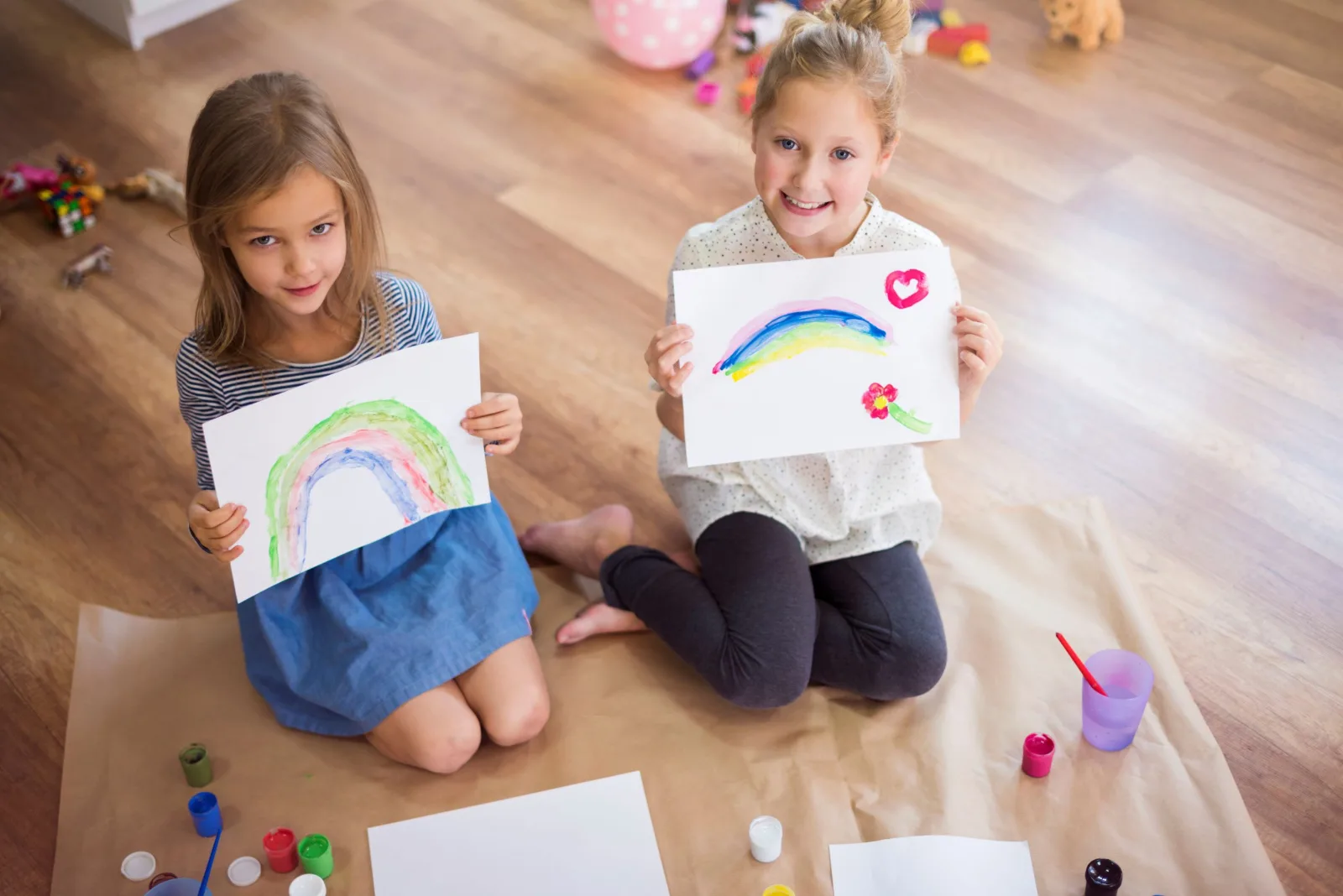 Two girls showing their rainbow drawings