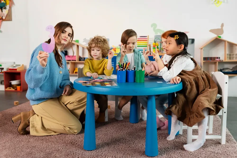 Teacher and three children at a round table in a nursery classroom