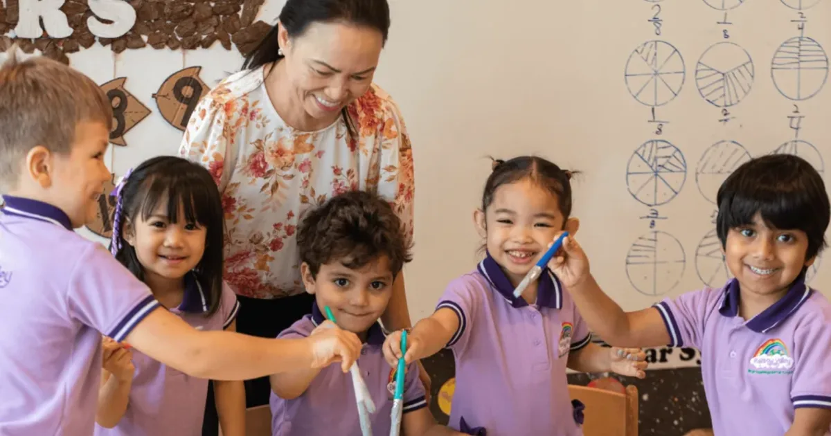 Rainbow Valley Nursery teacher and preschool children in lilac uniforms doing a hands-on activity